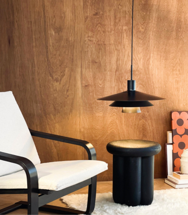 Dyberg Larsen pendant light above side table and armchair in a cosy atmosphere.