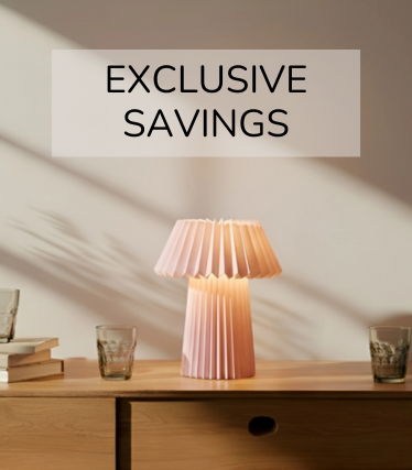 Pale pink table lamp on a wooden sideboard, surrounded by glasses and books in the warm sunlight.