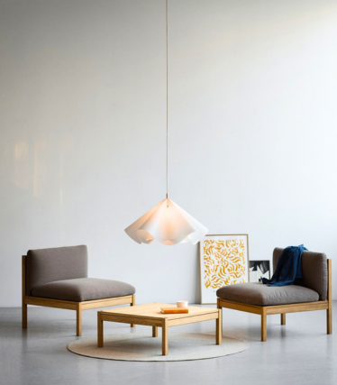 Light pendant lamp above low armchairs in a calm, minimalist room.