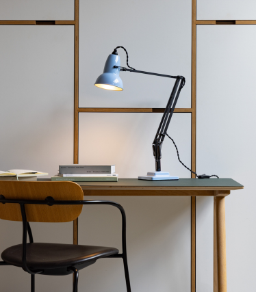 Light blue Anglepoise desk lamp on a wooden table with a chair