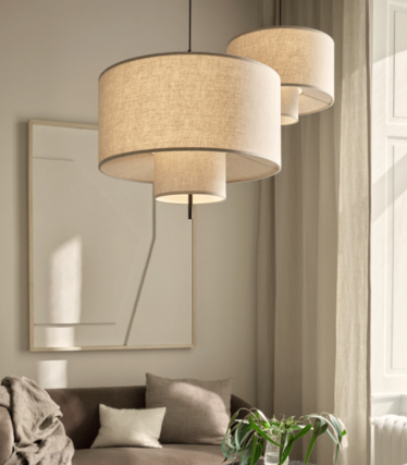 Two pendant lamps with layered linen shades above a beige sofa in a sunlit living room.