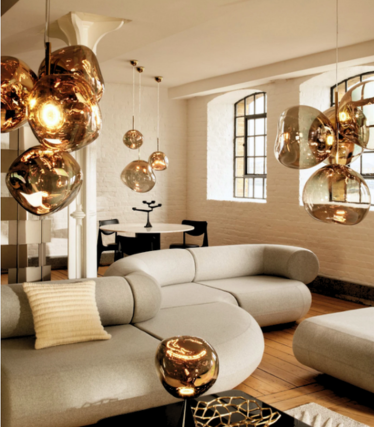 Gold-coloured Melt pendant lights above a light sofa in a loft with grid windows.